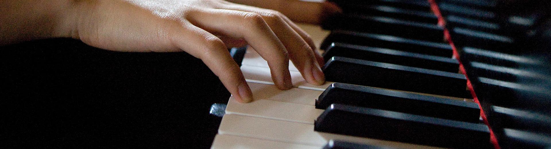 Six hands on piano keys playing a song